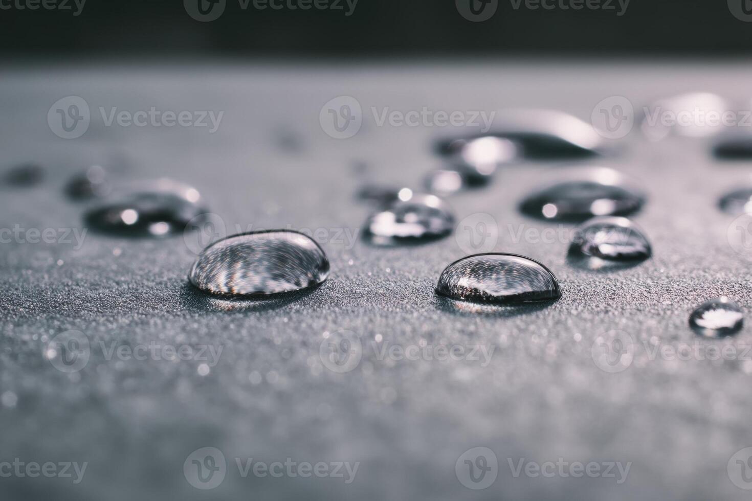 Droplets of water scattered on a smooth, textured surface with a shallow depth of field, focusing on a few droplets in the foreground while others blur into the background photo