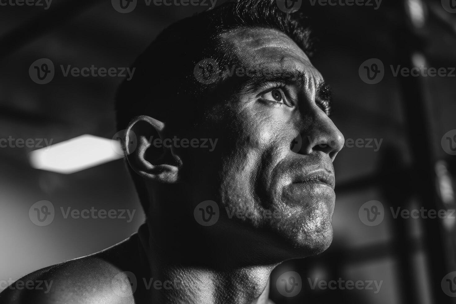 Close-up black and white portrait of a determined person with intense expression, strong facial features, and low lighting creating dramatic shadows, conveying focus and concentration photo