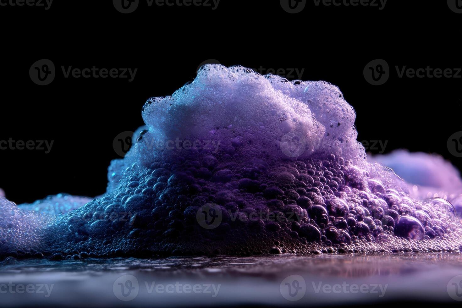 A foamy mound with purple and blue hues, illuminated against a dark backdrop, creates a dramatic, abstract display of texture and contrast in this captivating image of bubbles and light photo