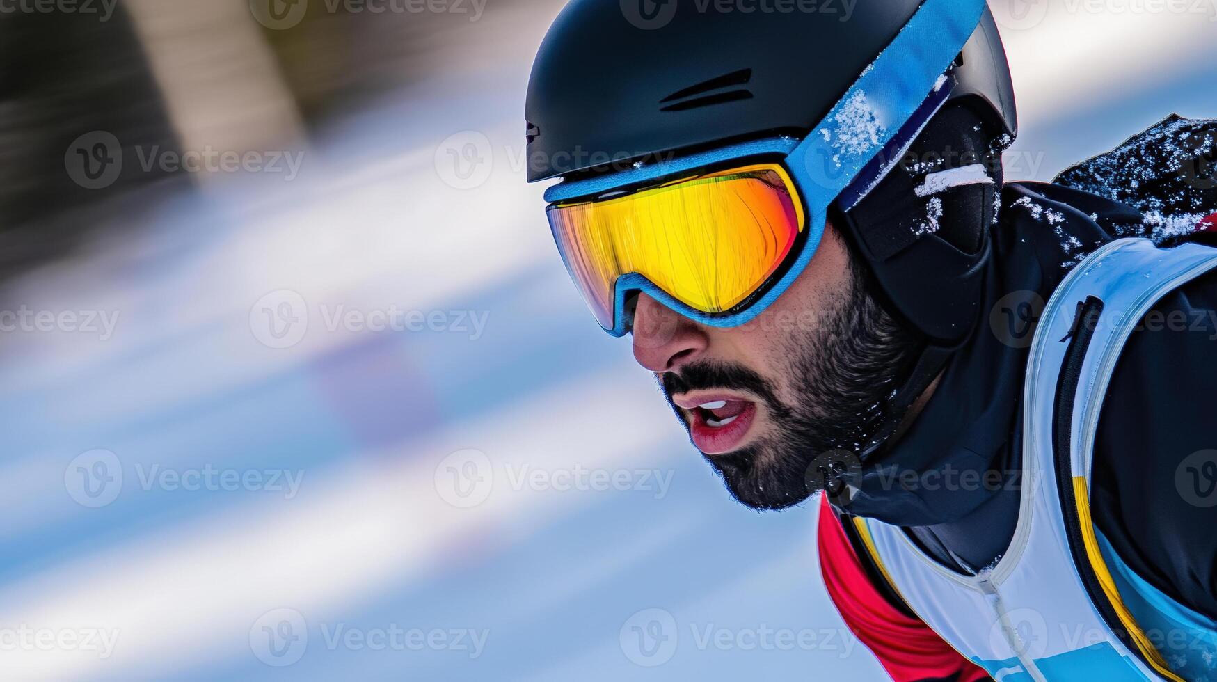 A focused skier in a helmet with reflective goggles and a serious expression races downhill. The background is blurred to show motion, and there's a hint of a snow-covered landscape photo