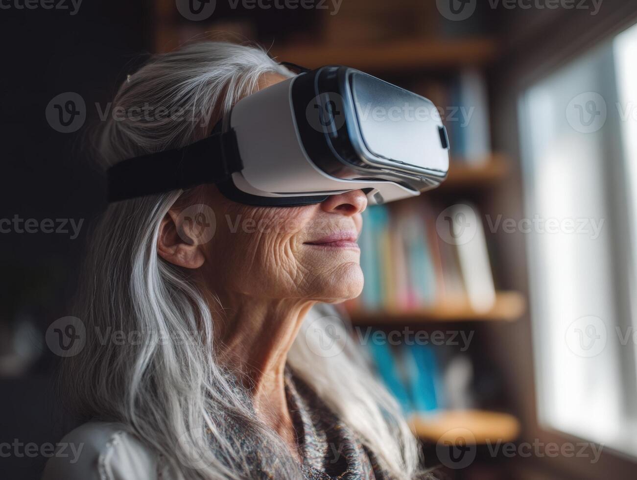 Elderly woman with long white hair wearing virtual reality headset, standing beside a window, with bookshelves blurred in the background, expressing curiosity and engagement photo