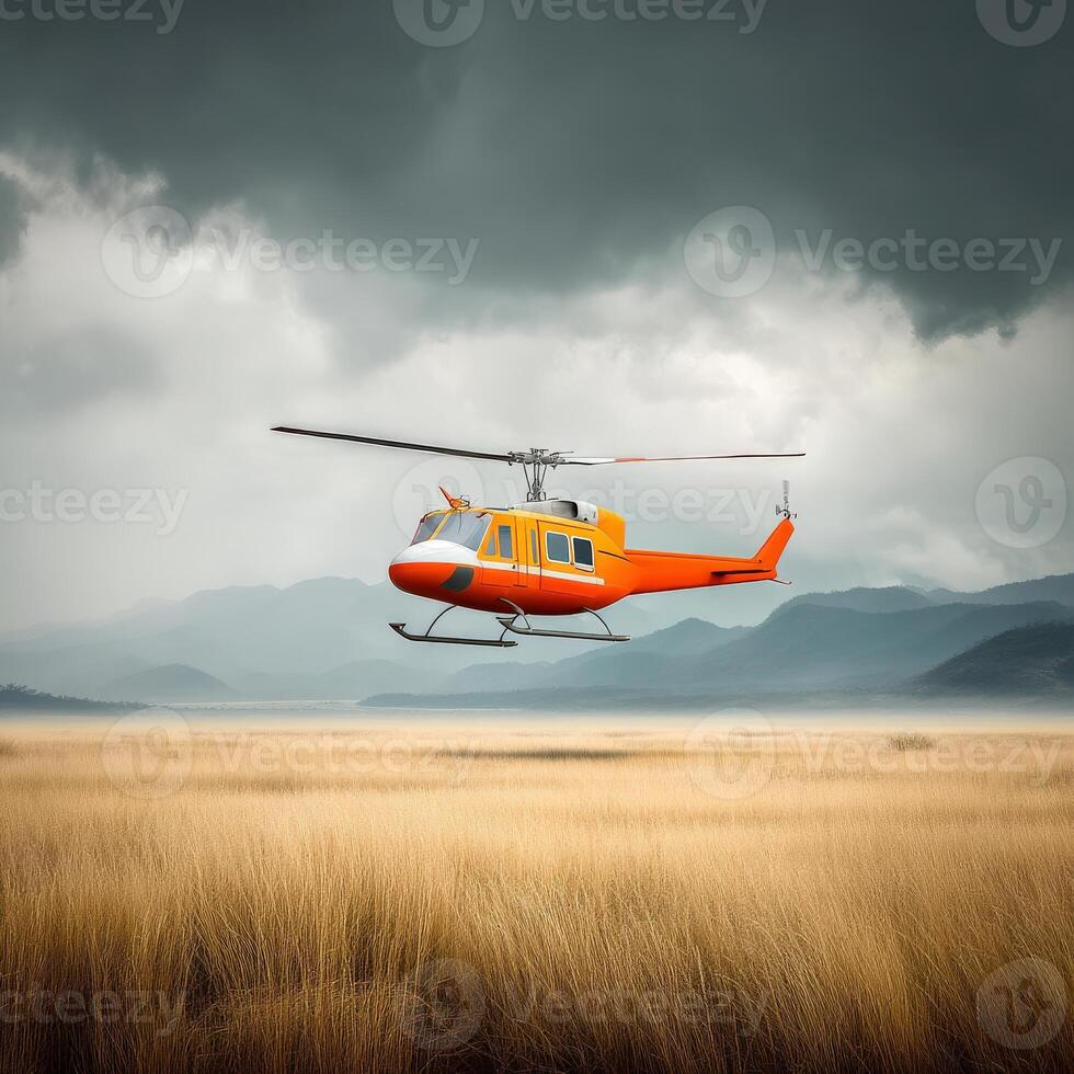 An orange helicopter flying over a field with mountains in the background photo