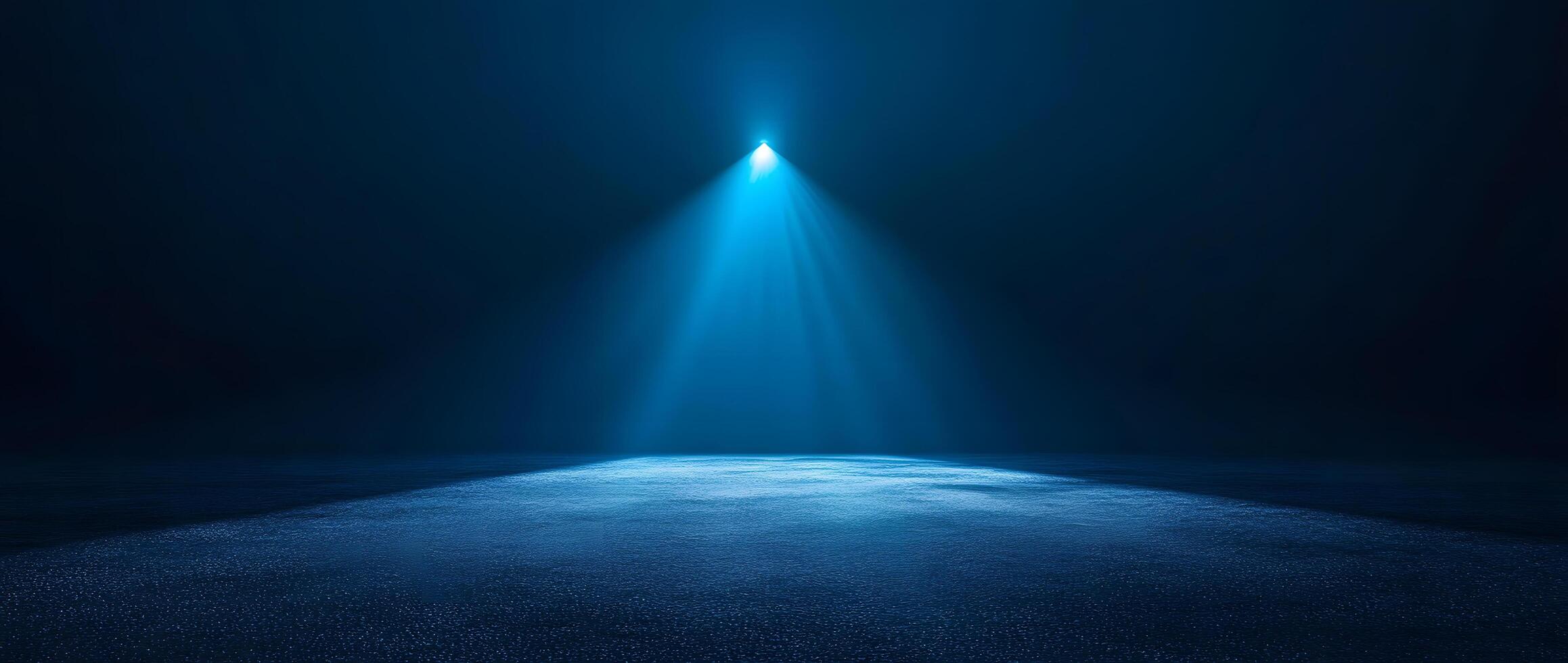An intense blue spotlight illuminates the dark void casting light down onto textured surface photo