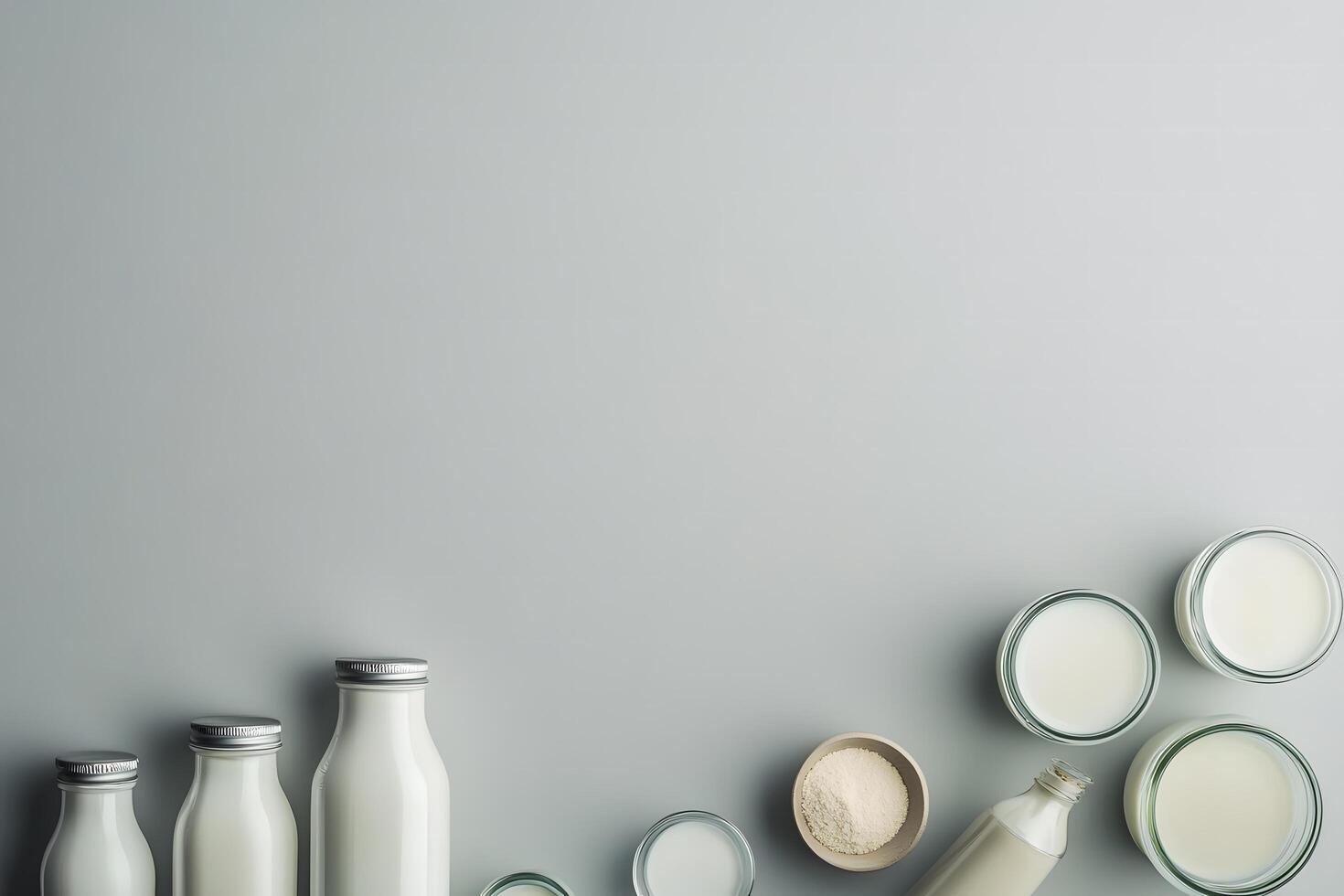 Glass bottles and bowls with milk and powder create a clean aesthetic on gray photo