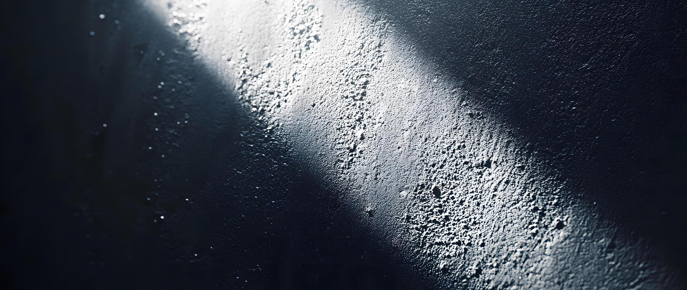 Light illuminates the textured surface of a dark wall creating a unique contrast photo