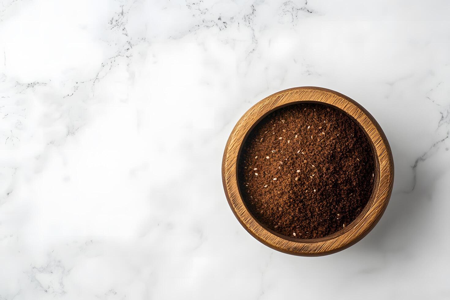 Overhead view shows a wooden bowl filled with dark brown zaatar seasoning photo