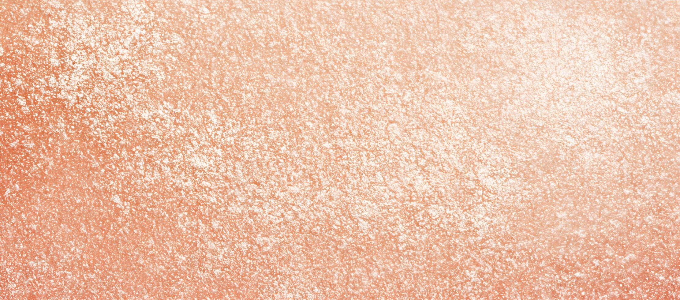 Peach colored grainy surface is covered with white specks creating a textured pattern photo