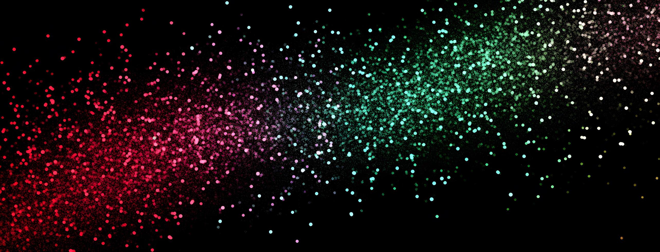 Red, pink and green particles create a sparkling colorful gradient effect against a black background photo