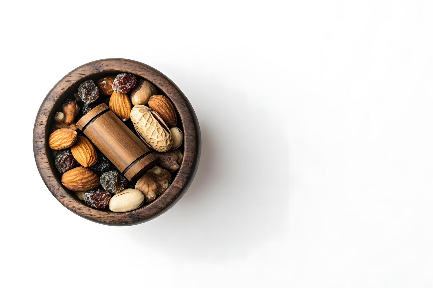 Round wooden bowl contains almonds, raisins, peanuts, hazelnuts, and a wooden nutcracker on white photo