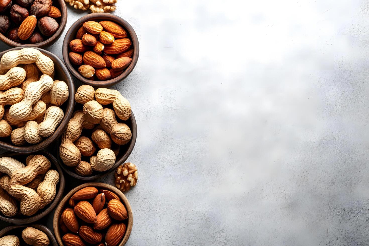 Rustic wooden bowls filled with assorted mixed nuts sit arranged on gray textured backdrop photo