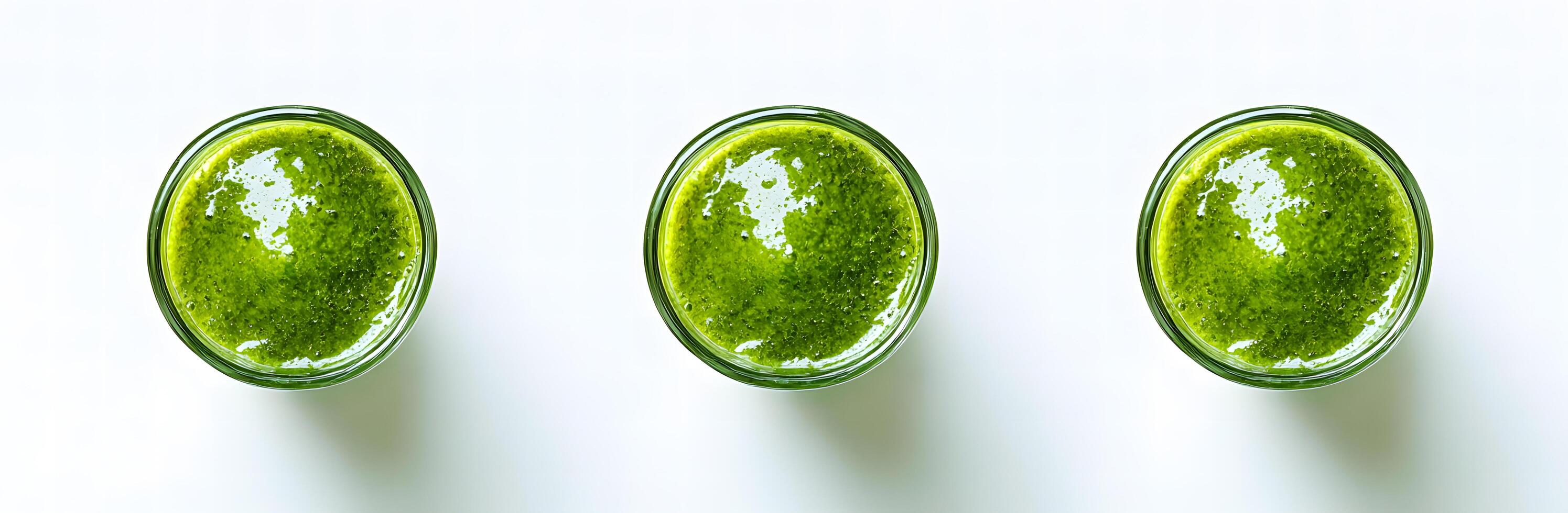 Three glasses of vibrant green smoothie are arranged elegantly on a bright white surface photo