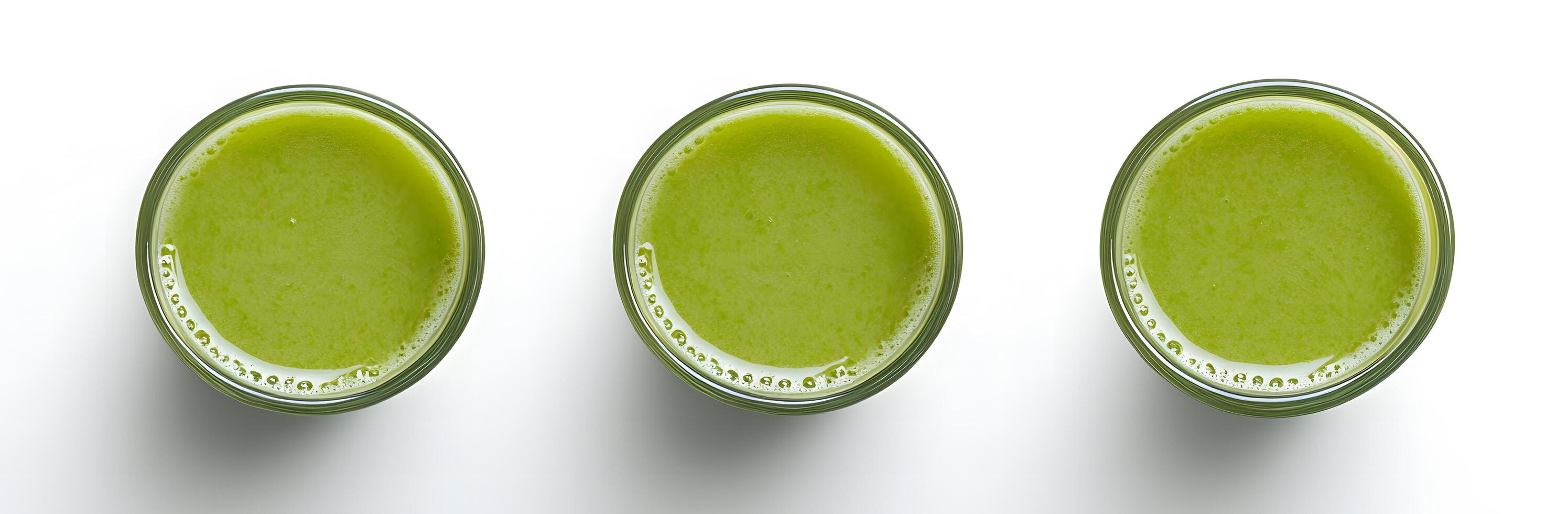 Three transparent glasses are filled with green smoothie, set against a bright white backdrop photo