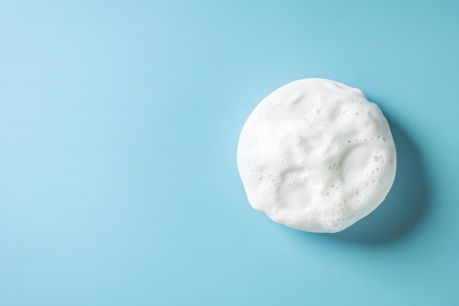 White foam with bubbles lies on a light blue surface in this image photo