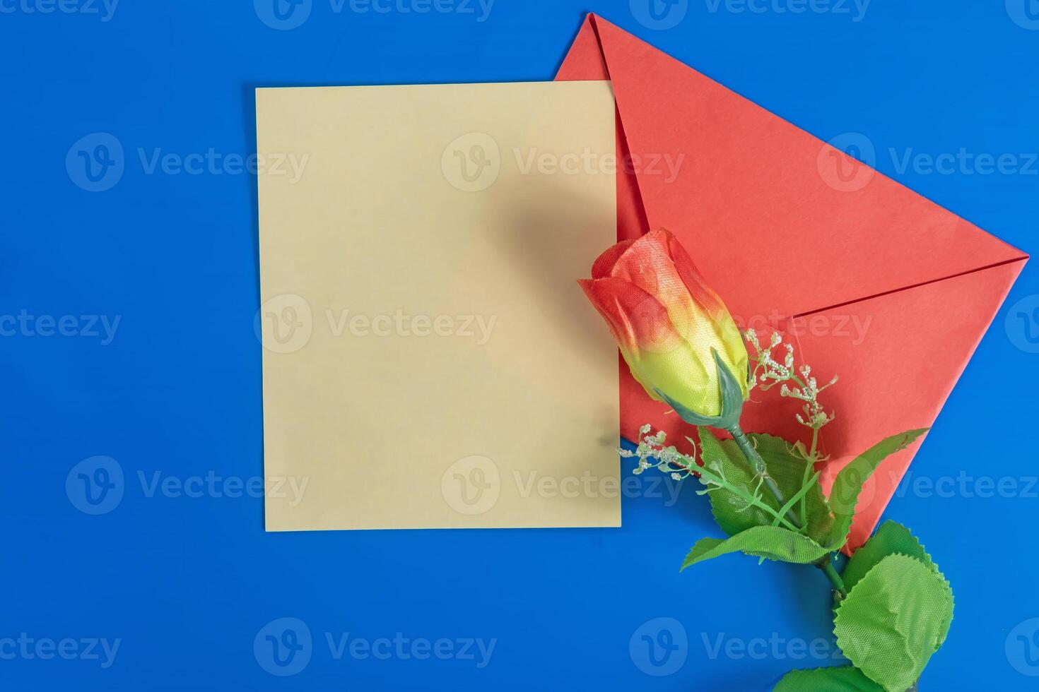 Red envelope with a blank card and a rose on a blue background. photo
