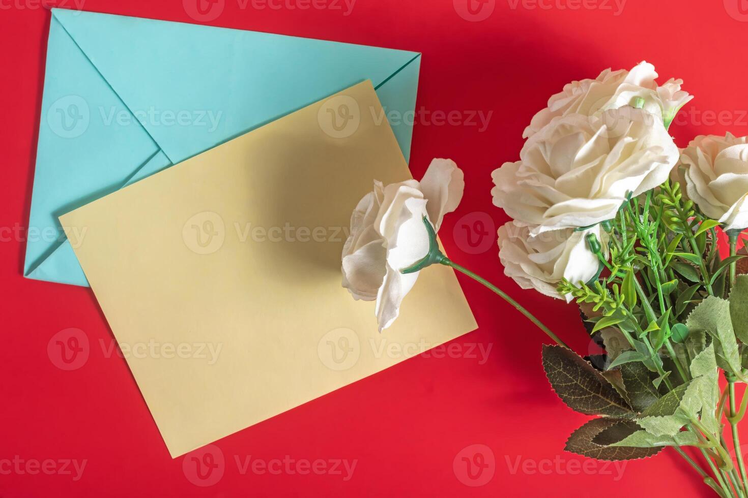 Festive card and white roses on a vibrant red background. Top view photo