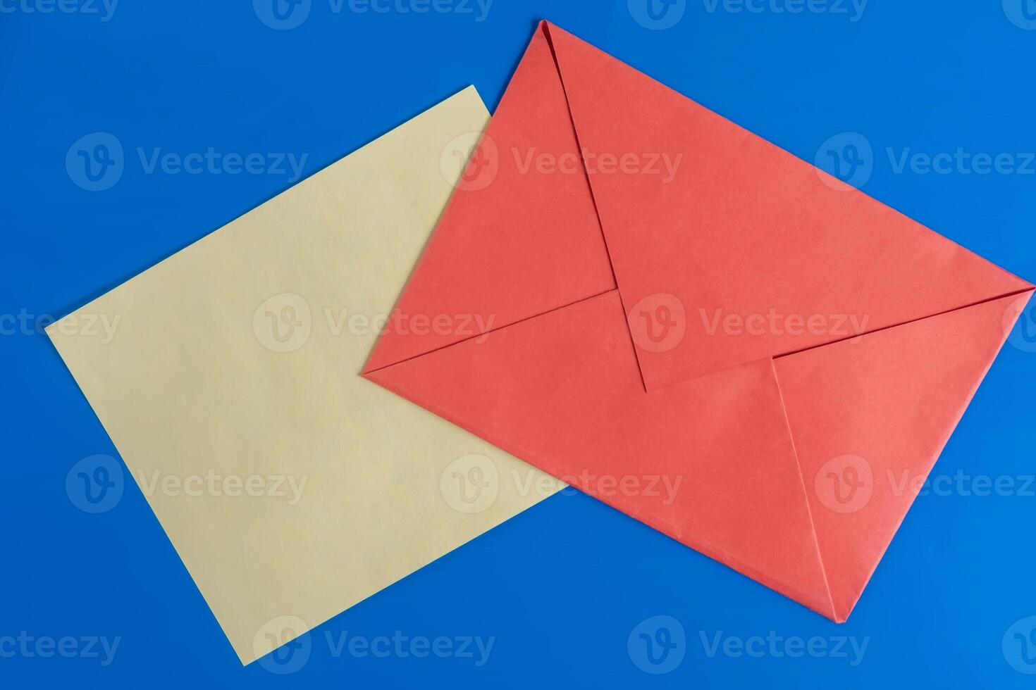 Bright red envelope with paper on a blue background surface. photo