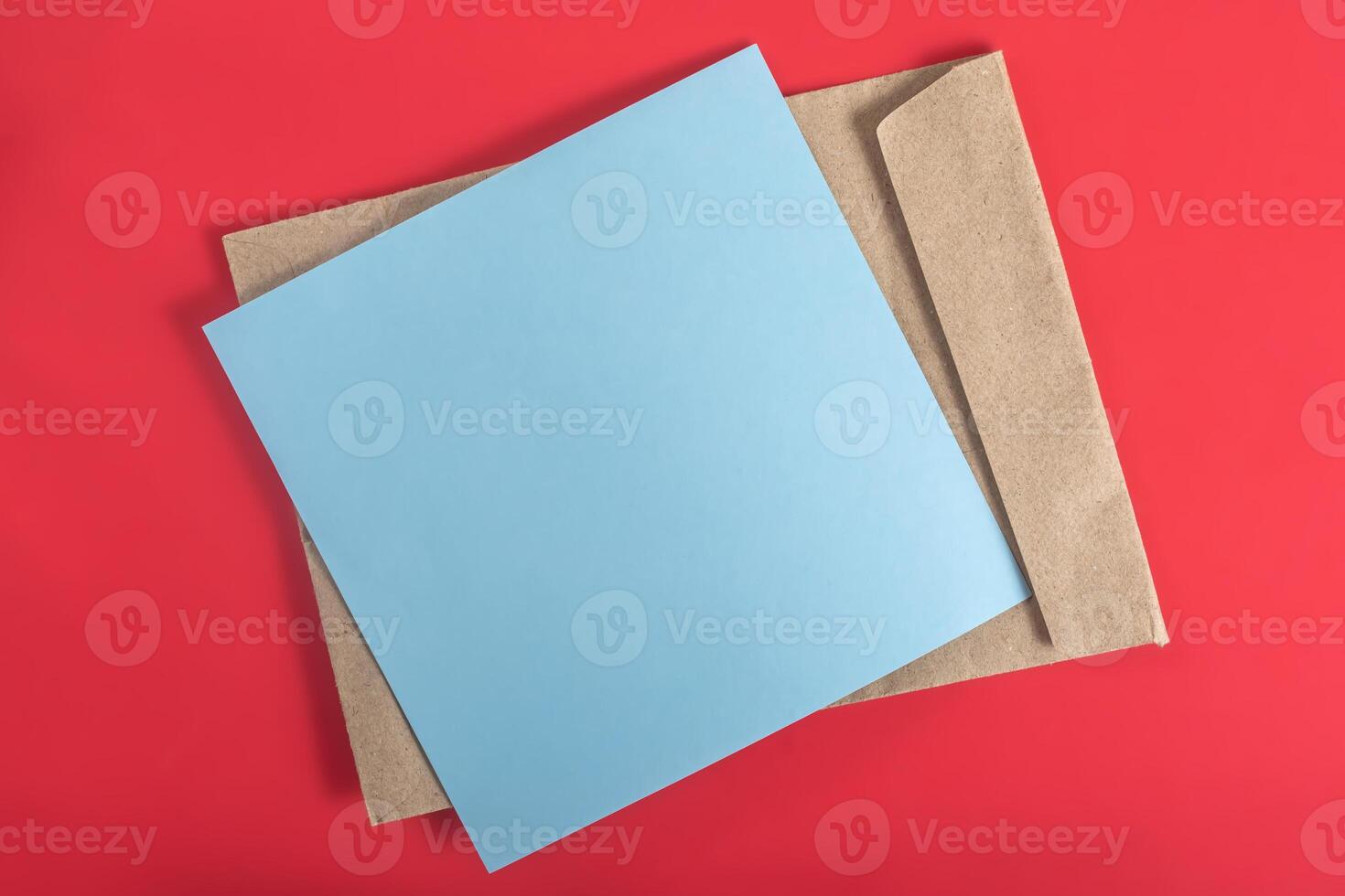 Blue paper sheet and brown envelope on a red background. photo