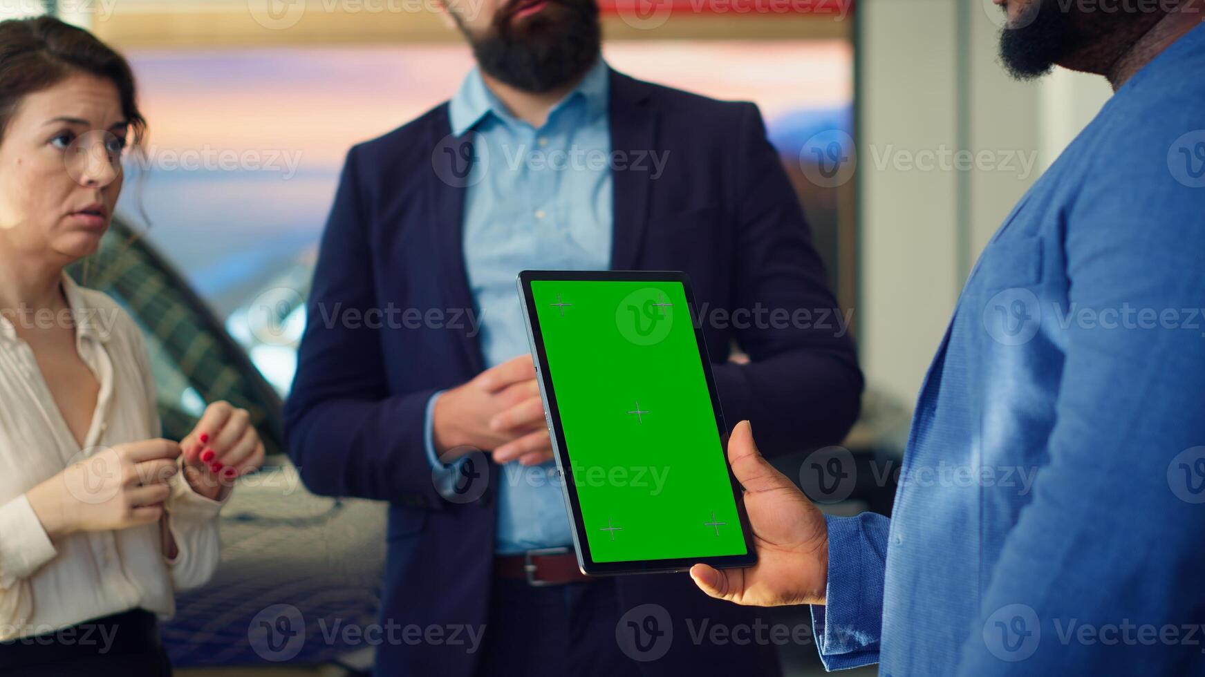 Dealership salesman showing car models on green screen tablet to clients, making recommendations. Showroom agent presents financing options to customers on chroma key device, camera A photo