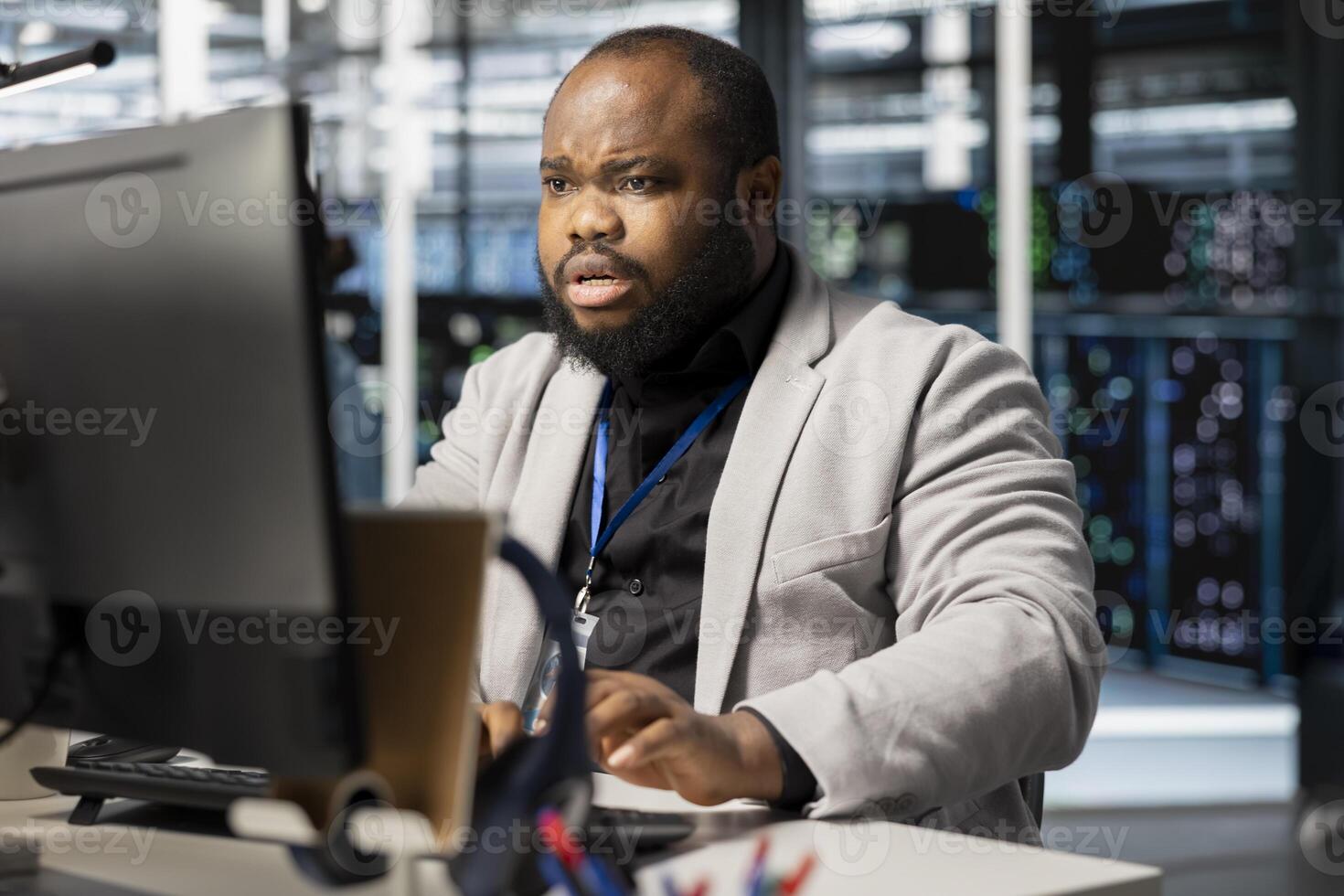 Worried server hub IT expert unnerved by infrastructure failure errors found during analysis. African american programmer in data center disturbed after detecting unexpected network outage photo