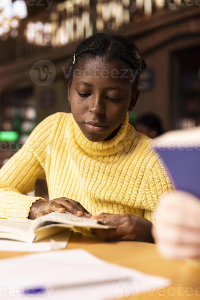 Preteen schoolgirl reading literature and taking notes for her academic curriculum in a productive library session. Scholar focusing on the mandatory lecture, developing her knowledge. photo