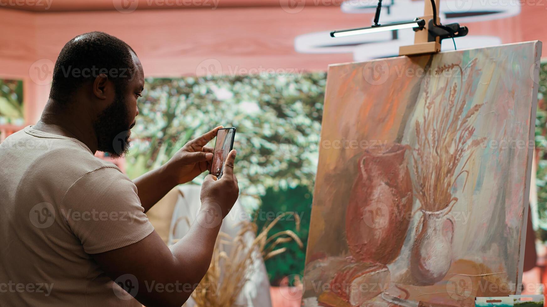 Painter applies watercolor paints on a canvas with a certain technique, creating a stunning piece of fine art. Artist uses vibrant colors and brushstrokes effects for his leisure activity. Camera A. photo