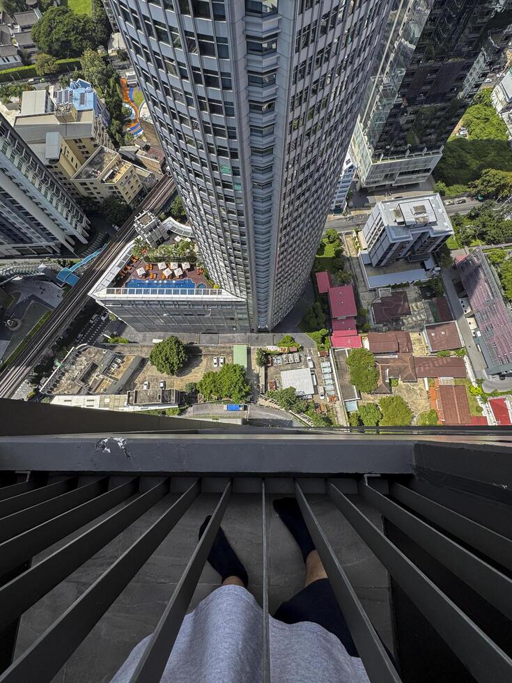 Bangkok, Thailand - November 11, 2024. Tourist high up in a skyscraper, looking down from the big window and capturing the luxurious skyline view on a bustling Thai metropolis. photo