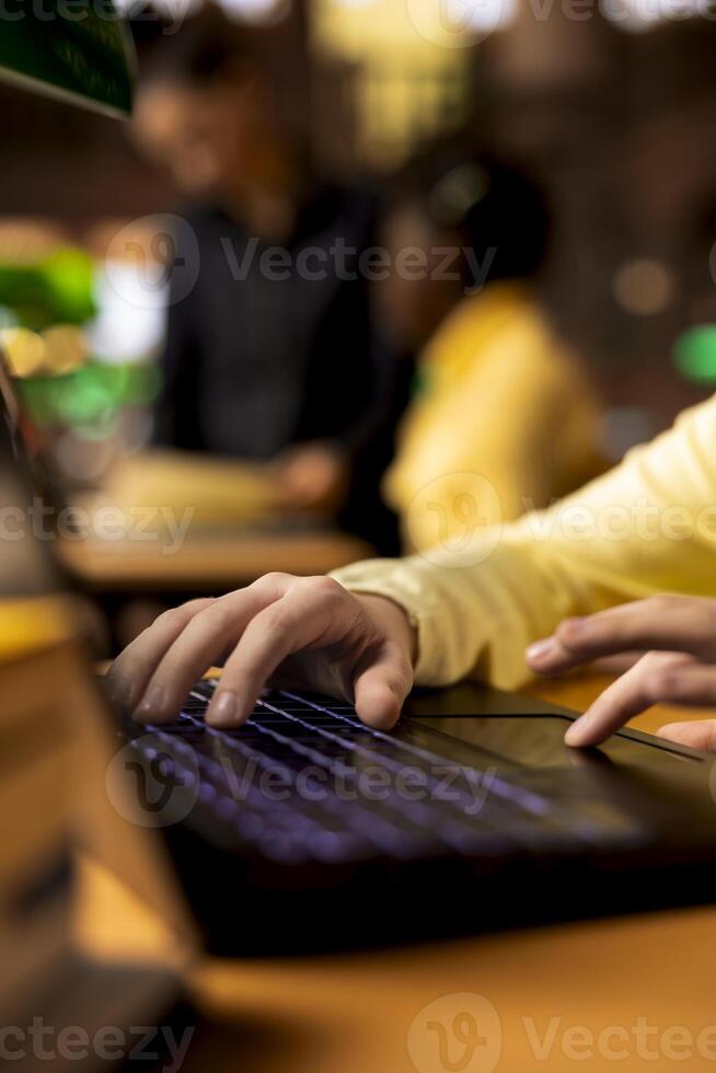 Elementary school pupil writing essay on laptop using research from library books, completing school assignments developing academic skills through study sessions. Educational activities. Close up. photo