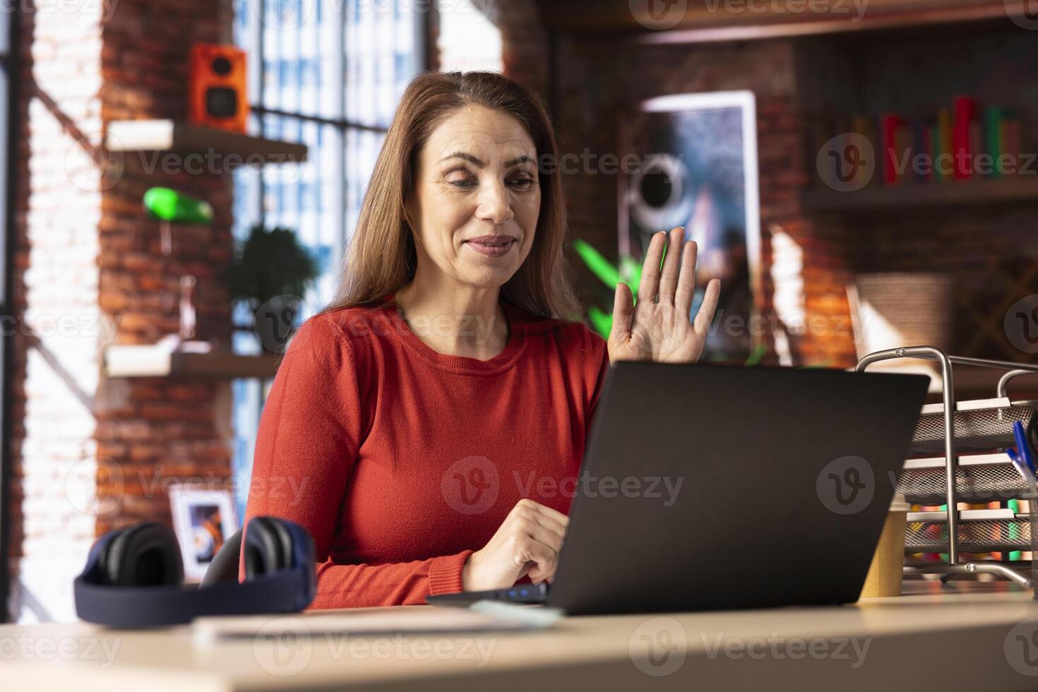 Woman freelancer taking online course to develop new skills from home office, attend online call and watching lecture from her loft. Person participates at a virtual training class. photo
