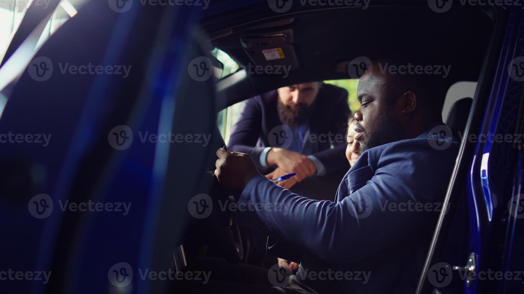 Customers in showroom car filling feedback form after finishing test drive and deciding to make purchase, satisfied with salesman help. Couple buying automobile after being pleased with it, camera B photo