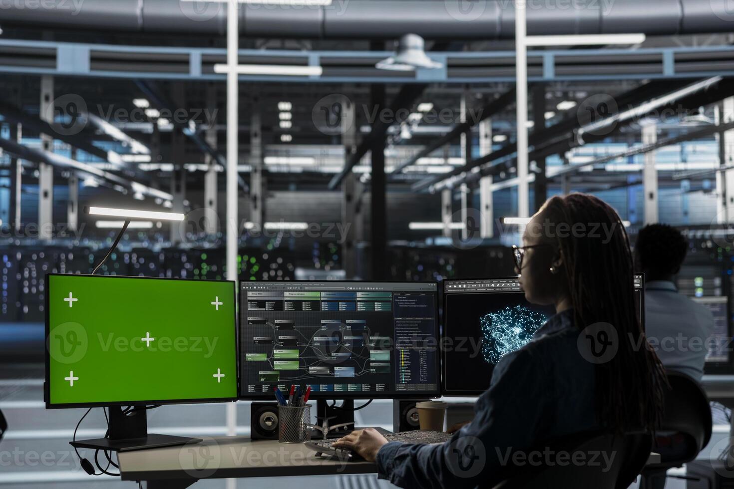 Admin working on green screen desktop PC in data center housing storage infrastructure. IT specialist using mockup computer display in server hub workspace filled with networking tech photo