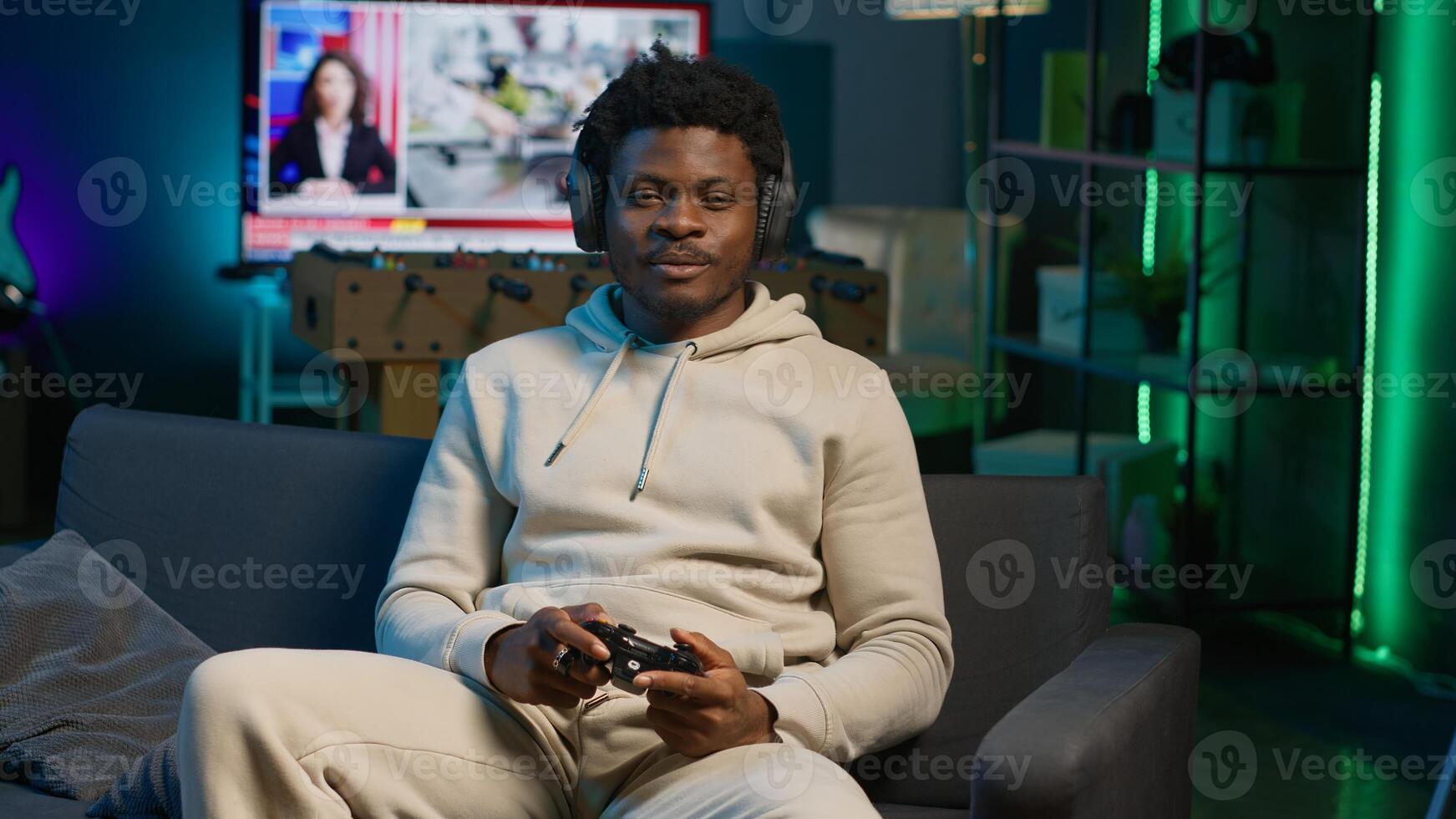African american man playing shooter videogame in his loft apartment, holding controller for leisure activity. Male gamer participating in internet multiplayer game at night. Camera A. photo