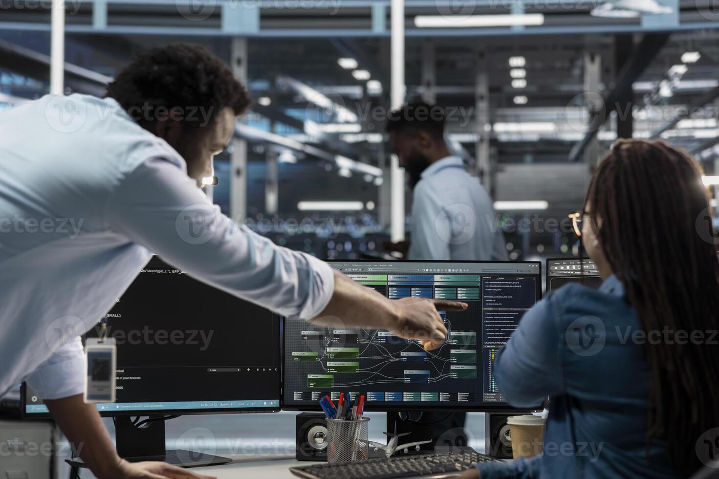 Data center supervisor overseeing admin using PC to visualize artificial intelligence neural networks node trees. Server room manager providing feedback to employee working to oversee AI systems photo