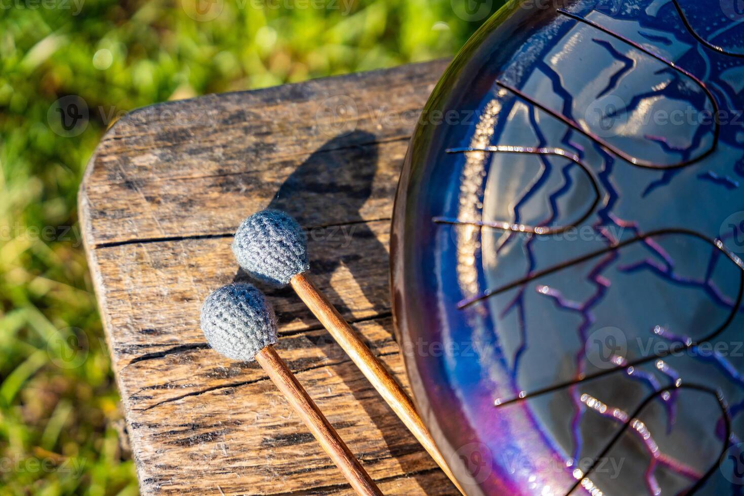 Steel tongue drum and mallets resting on a wooden bench. Concept of sacred stillness, sound meditation, and harmony with nature. High quality photo