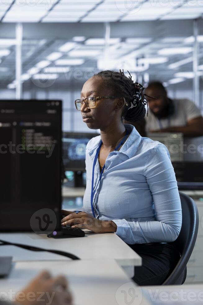 System administrator in data center managing and optimizing IT infrastructure using network management skills. African american server room worker upgrading equipment, reducing operational costs photo