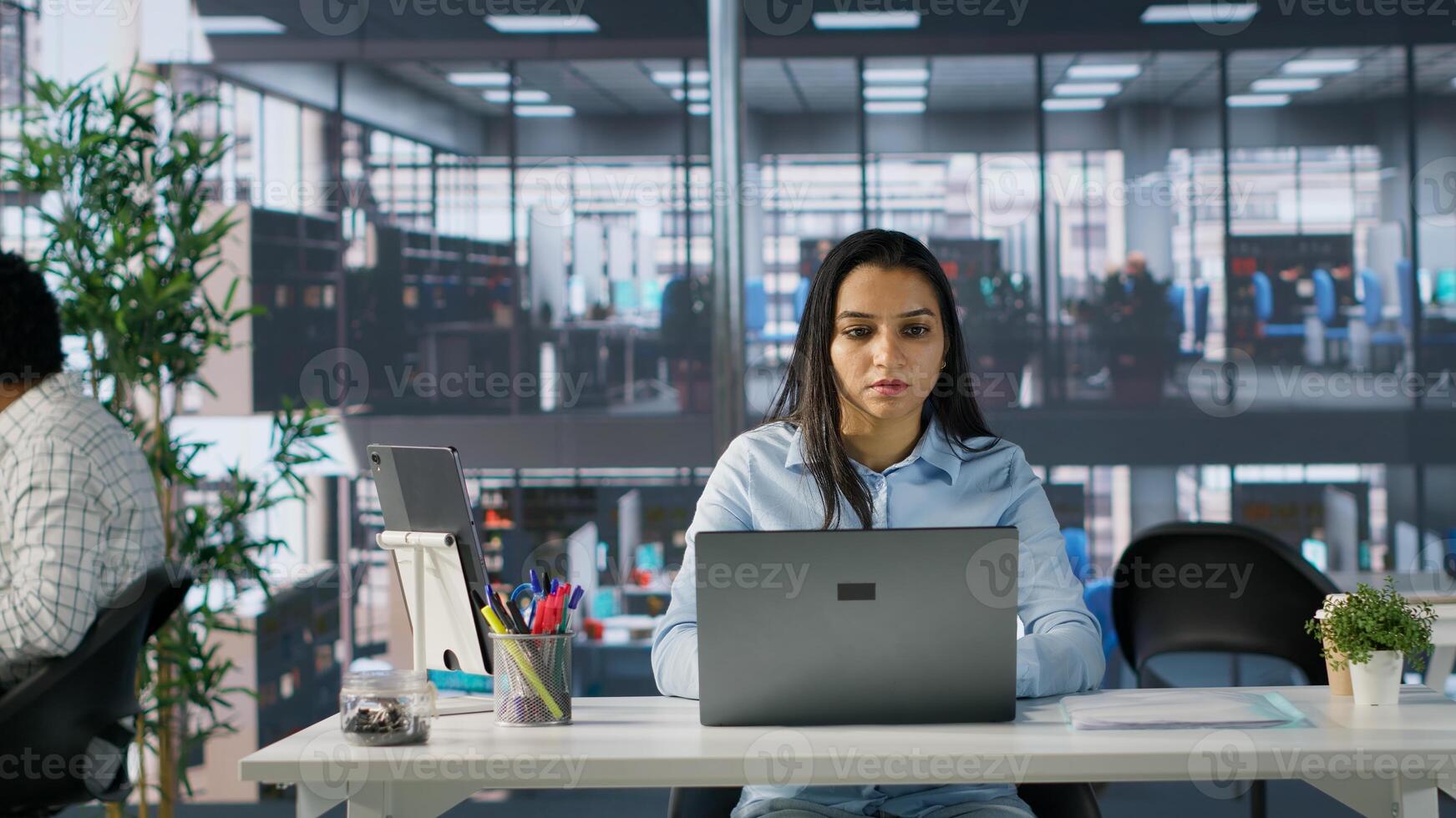 Indian female manager at her office desk working on report writing, financial planning and deadline management. Expert specialist reviewing objectives and goals to ensure success. Camera A. photo