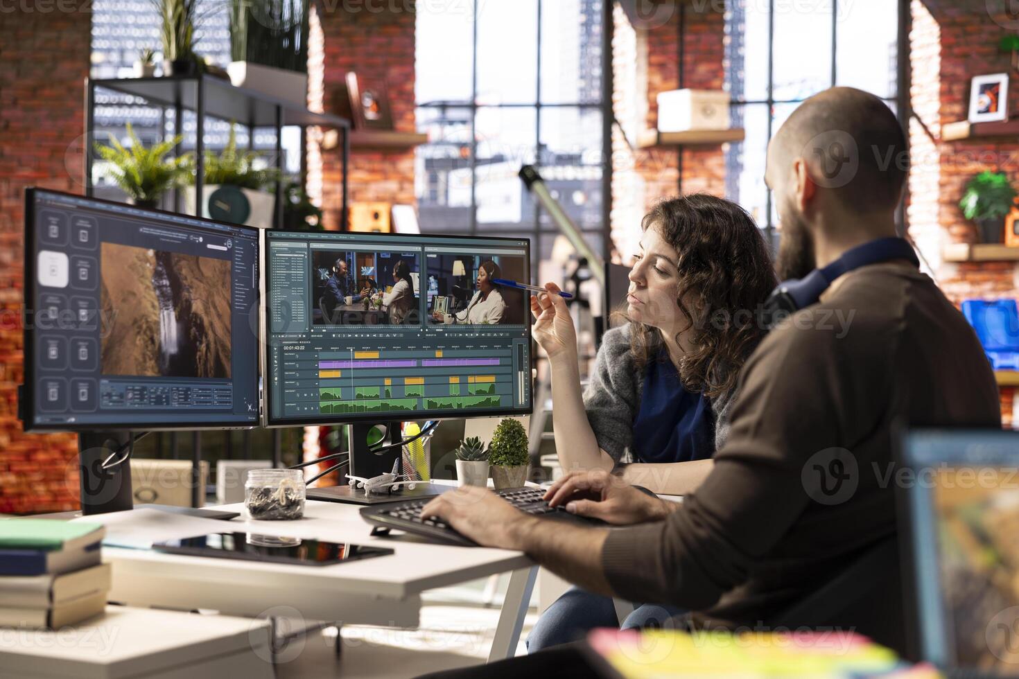 Man and woman filmmakers editing a shoot in post production, using a modern tech setup and editing software for a creative project. Modern workspace with dual monitors. photo
