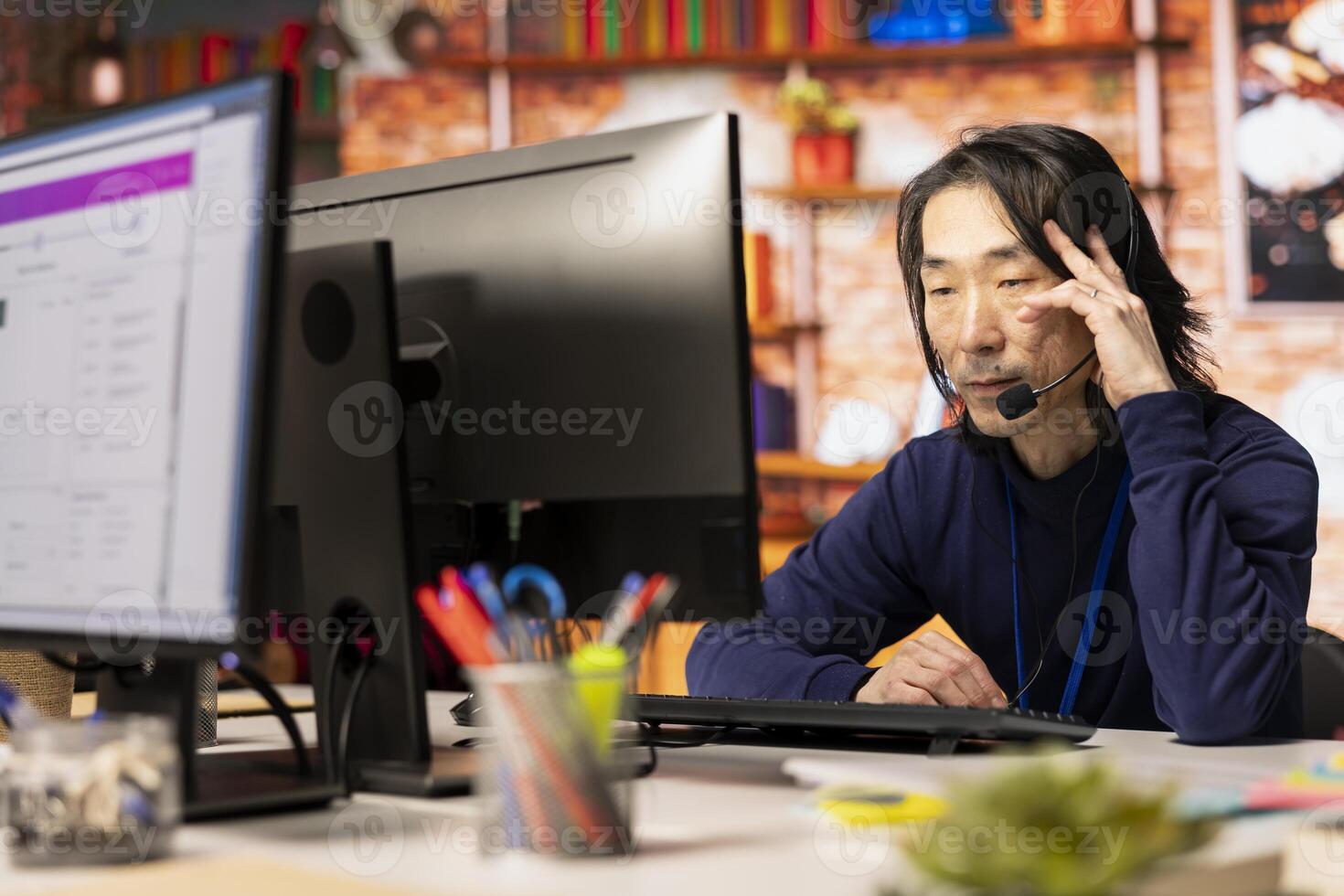 Call center agent speaking in audio headset microphone, using remote access tools. Worker in customer center assisting clients with installing software, communicating through headphones mic photo