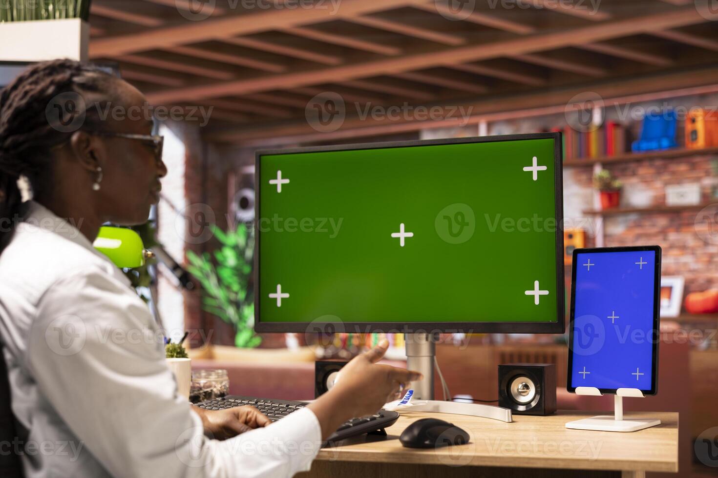 Remote worker typing on chroma key screen PC and mockup tablet, doing project tasks in home office. African american teleworker using isolated screen devices, doing research for company project photo