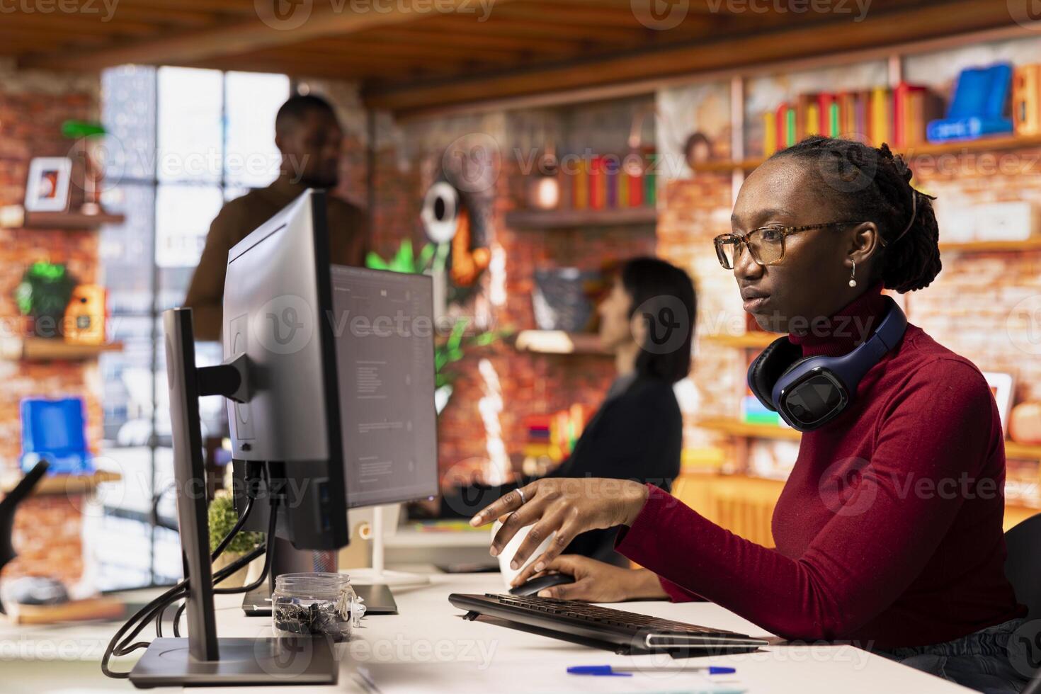 Programmer in startup office using large language model to get help with coding project. African american worker interacting with AI LLM chatbot PC GPT software on PC in software development workplace photo