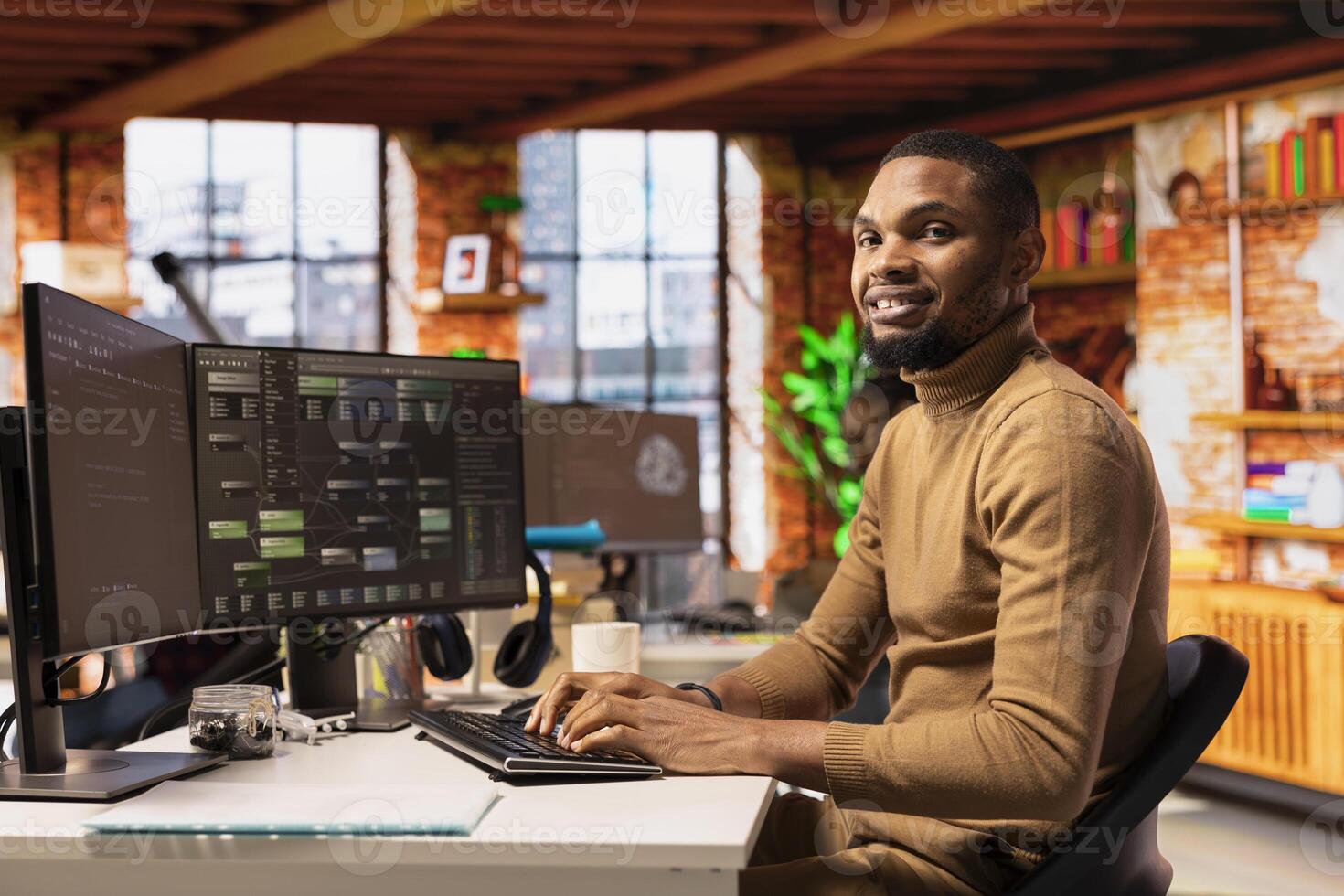Portrait of cheerful IT technician using PC in innovative startup office and programming languages to build applications. Joyous software development agency IT expert optimizing code on computer photo