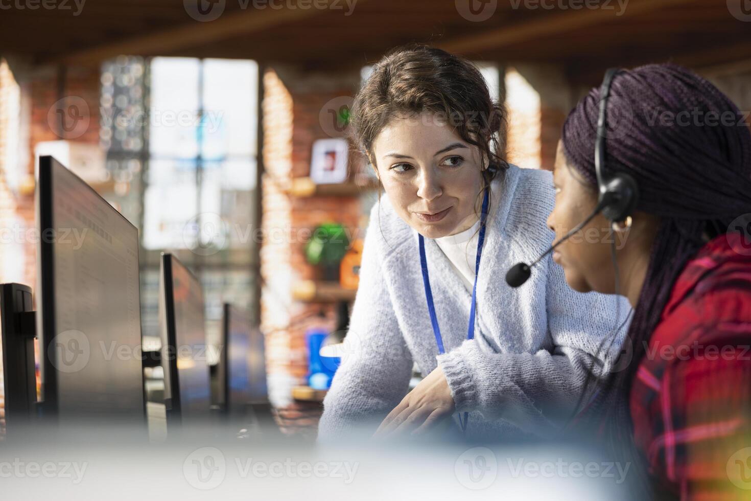 Smiling call center manager providing guidance to intern, addressing questions. Friendly customer support workplace onboarding specialist conducting orientation sessions for new worker photo