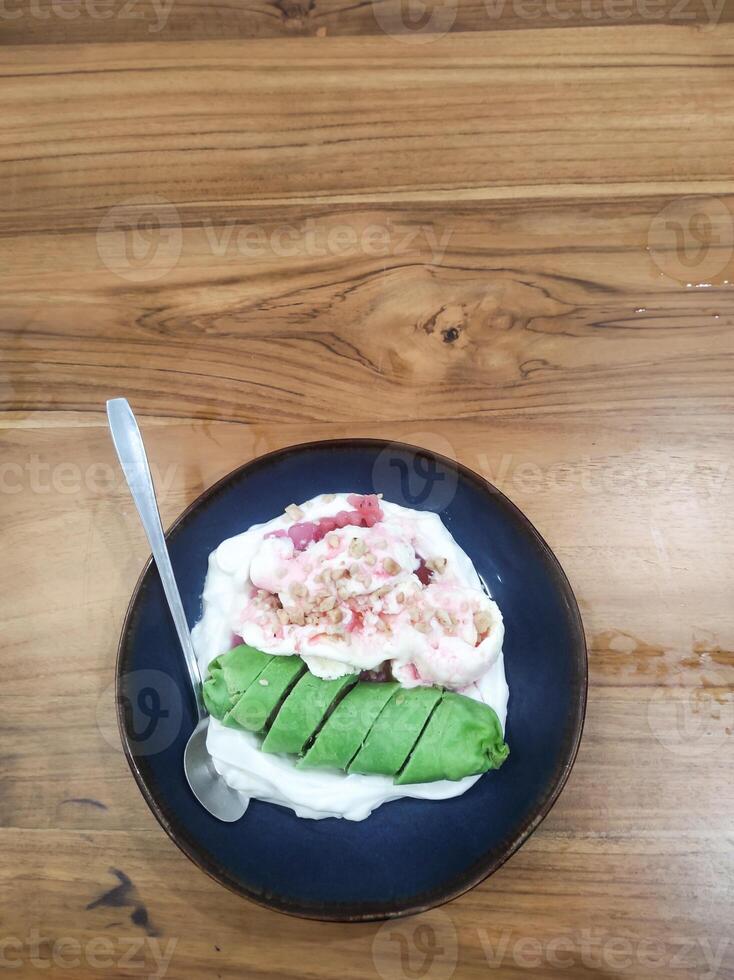 Green banana ice, a traditional dessert from Makassar, Indonesia. A dish of bananas wrapped in green dough, served with marrow porridge, red syrup, ice cream and roasted peanuts. Copy space photo