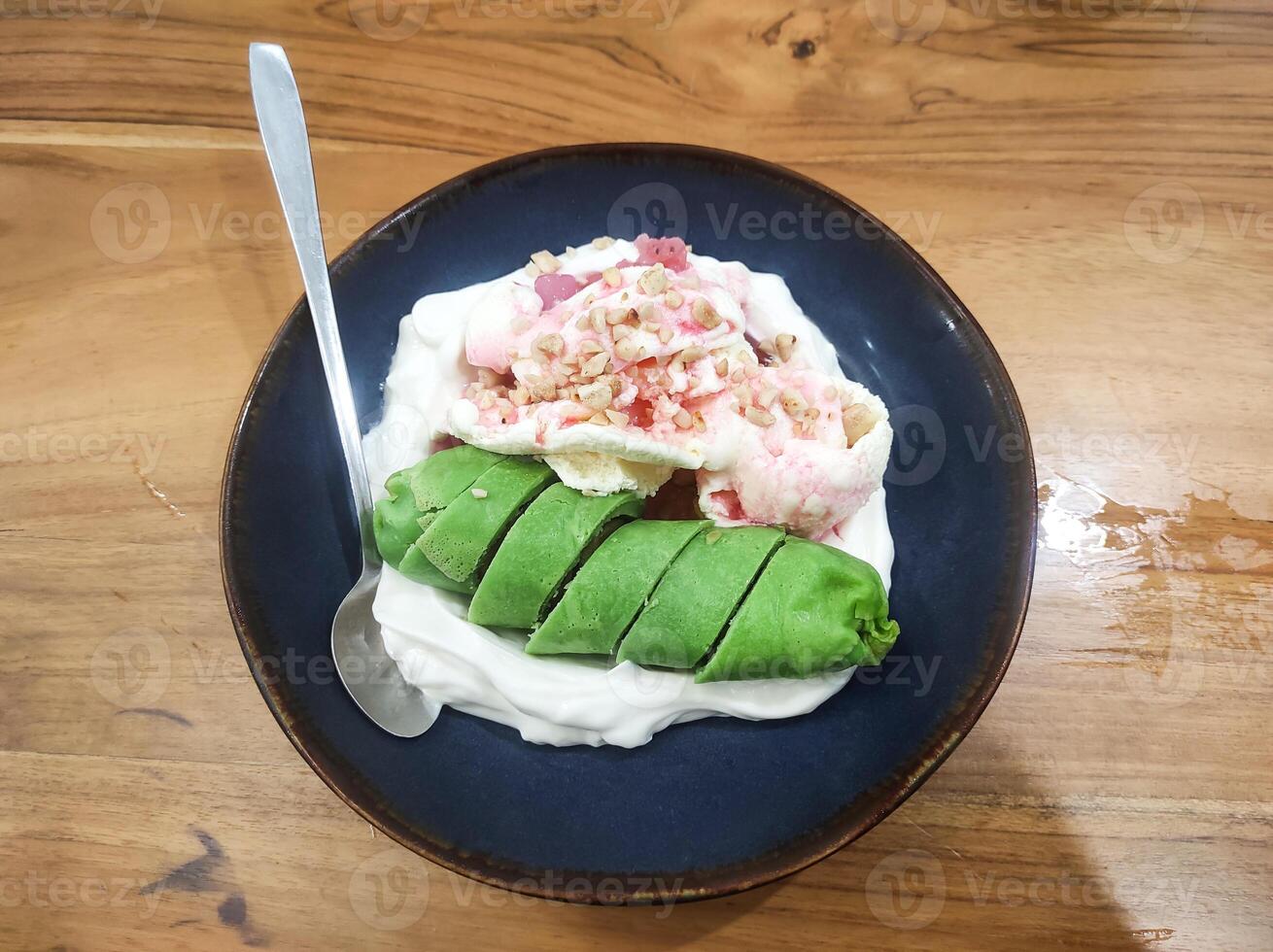 Table top view Es Pisang Ijo, a typical dessert from Makassar, Indonesia. A dish of bananas wrapped in green dough, served with sumsum porridge, red syrup, ice cream. photo