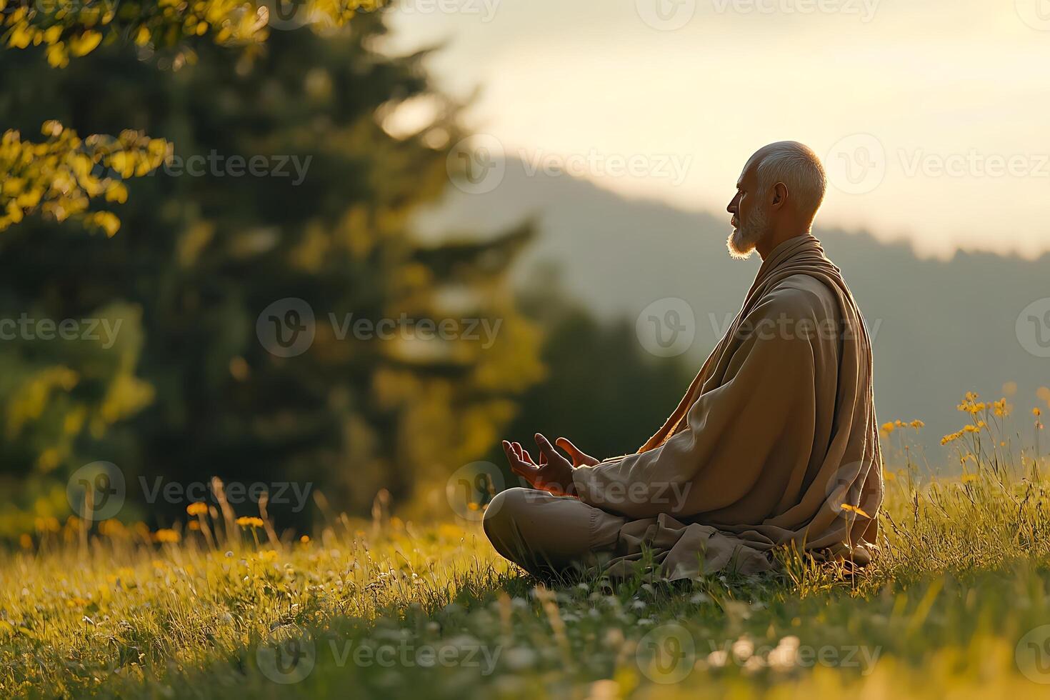 A man meditating in the grass with mountains in the background photo