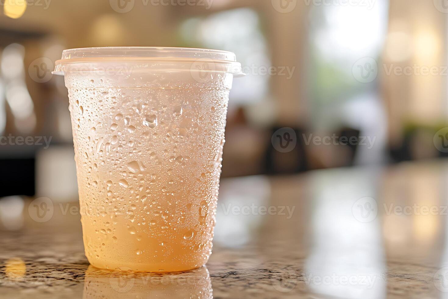 A plastic cup with a drink sitting on a counter photo