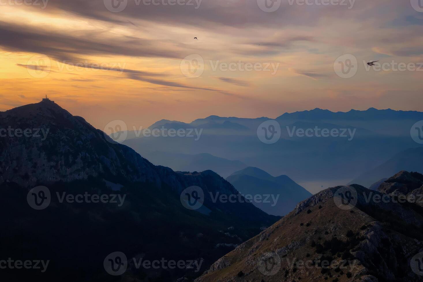 Scenic sunset over a dramatic mountain range with layered ridges fading into the distanc photo