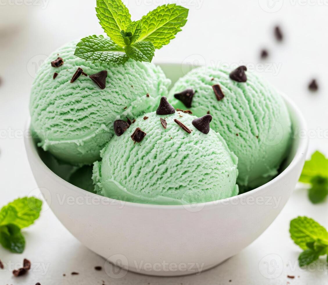Close-up of a white bowl filled with three scoops of mint creamy ice cream, garnished with a mint. photo