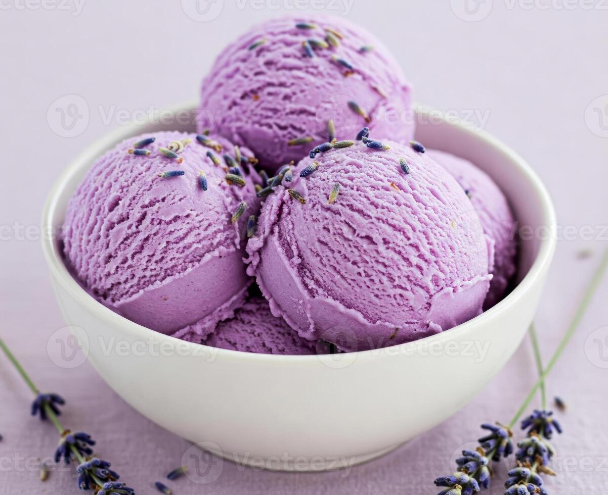 Close-up of a white bowl filled with three scoops of lavender creamy ice cream, garnished with a lavender photo