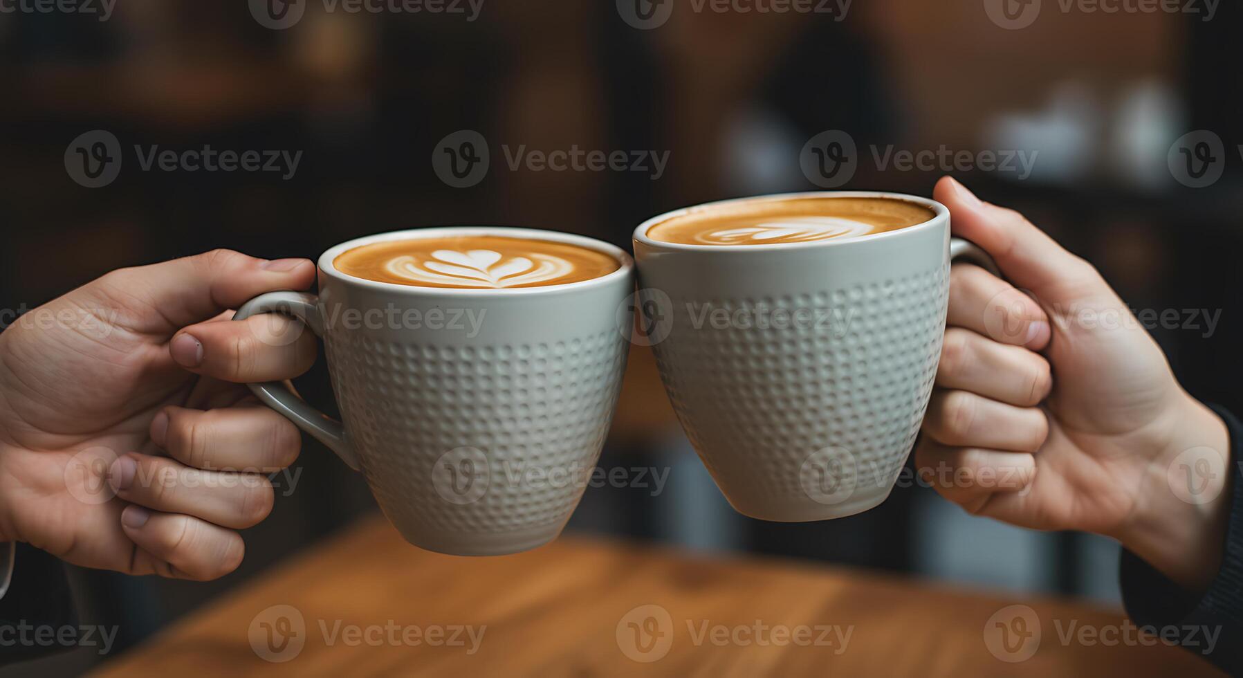 Two People Toasting with Textured Ceramic Mugs of Latte Coffee in Cozy Cafe Setting photo