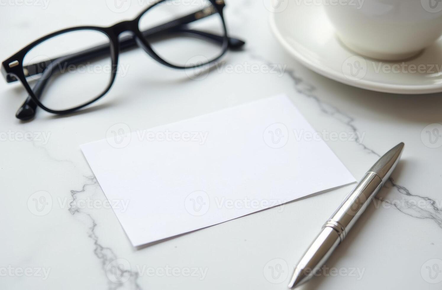 A blank note card and pen next to reading glasses and a coffee cup on a marble table in a cozy workspace during the afternoon photo